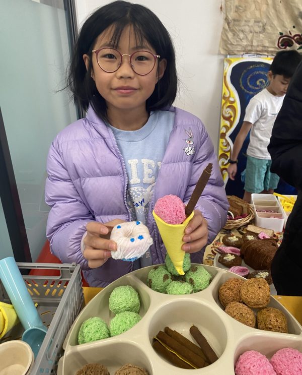 A child serves pretend ice-cream made out of coloured sponges and recycled materials